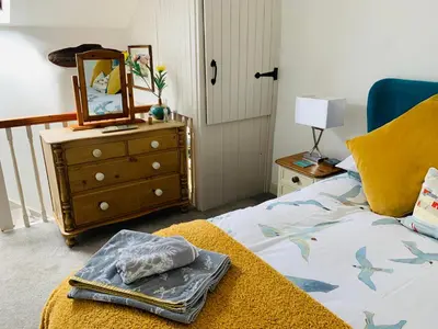 a bedroom with a bed with a dresser and a mirror at Cockle Bay Cottage in Morecambe