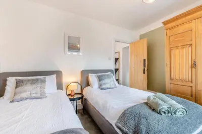 a bedroom with two beds and a wooden cabinet at 3 Bed in Newton In Cartmel oc-a29796 in High Newton