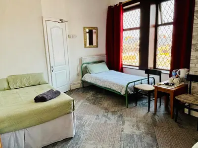 a bedroom with two beds and a table and window at Leatham Park Hotel Blackpool in Blackpool