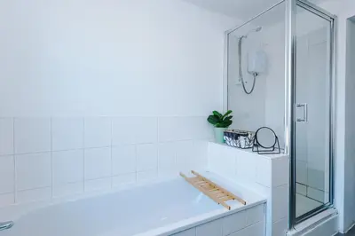 a white bathroom with a tub and a glass shower at Private garden maisonette near city centre! Walking distance from Anfield in Liverpool