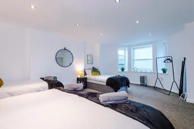 a white room with two beds and a mirror at Private garden maisonette near city centre! Walking distance from Anfield in Liverpool