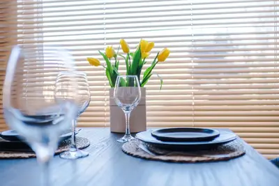 a table with two wine glasses and a vase with yellow flowers at Private garden maisonette near city centre! Walking distance from Anfield in Liverpool