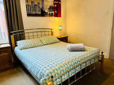a bedroom with a bed with a blue comforter at Le Papillon Hotel Blackpool in Blackpool