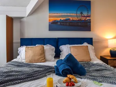 a bed with a blue head board with a plate of food on it at Drumford in Blackpool