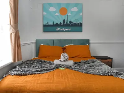 a bed with an orange comforter and a blanket at Drumford in Blackpool