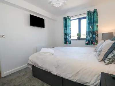 a bedroom with a bed with blue curtains and a window at Priestleys Retreat in Blackburn