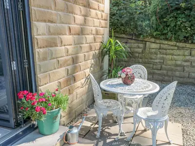 a patio table and chairs with a vase on it at Priestleys Retreat in Blackburn