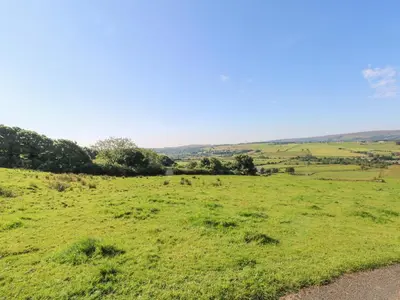 a field of green grass with trees in the distance at Priestleys Retreat in Blackburn