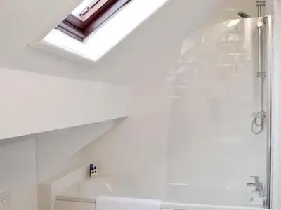 a bathroom with a shower and a bath tub with a skylight at The Rafters Bank House Stunning Apartment in Millom