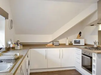 a kitchen with white cabinets and a white sink at The Rafters Bank House Stunning Apartment in Millom