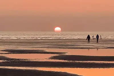 a group of people walking on the beach at sunset at Estuary View Bank House Stunning apartment in Millom