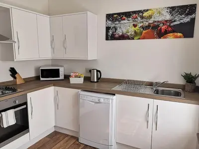 a kitchen with white cabinets and a sink at Estuary View Bank House Stunning apartment in Millom