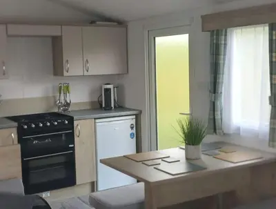 a kitchen with a stove and a table in it at Sea breeze, modern, cosy holiday home in Haverigg