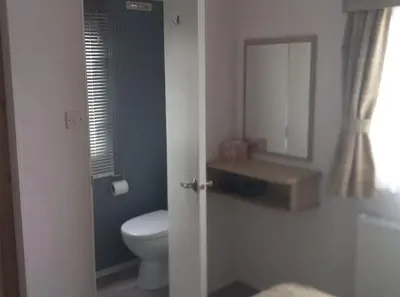 a bathroom with a toilet and a sink and a mirror at Sea breeze, modern, cosy holiday home in Haverigg