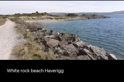 a white rock beach harvesting sign next to a body of water at Nadia's Lodge Smart TV & Wi-Fi in Haverigg