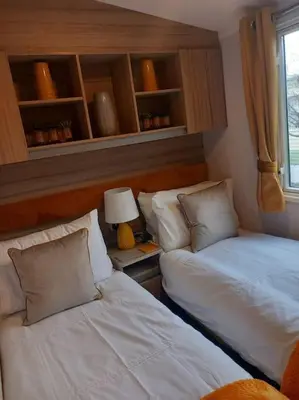 a bedroom with two beds and a lamp and a window at Nadia's Lodge Smart TV & Wi-Fi in Haverigg