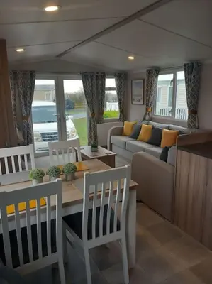 a living room with a couch and a table and chairs at Nadia's Lodge Smart TV & Wi-Fi in Haverigg