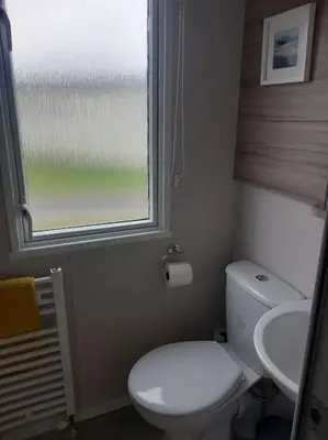 a small bathroom with a toilet and a sink at Nadia's Lodge Smart TV & Wi-Fi in Haverigg