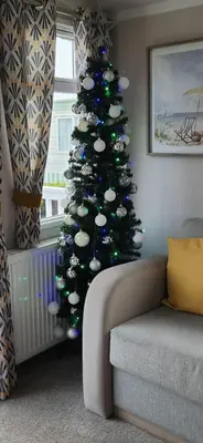 a christmas tree in the corner of a living room at Nadia's Lodge Smart TV & Wi-Fi in Haverigg