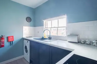 a blue kitchen with a sink and a washing machine at Charming 1 Bedroom Apartment in Central Liverpool in Liverpool