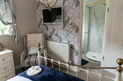 a bedroom with a bed and a shower and a chair at Peacock Room at Field View Cottage in Eccleston
