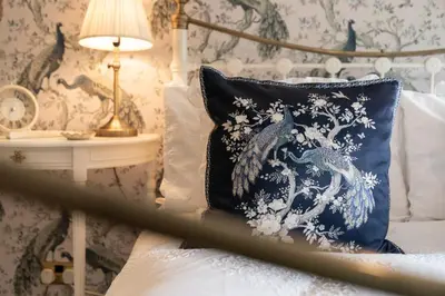 a blue pillow sitting on a bed with a lamp at Peacock Room at Field View Cottage in Eccleston