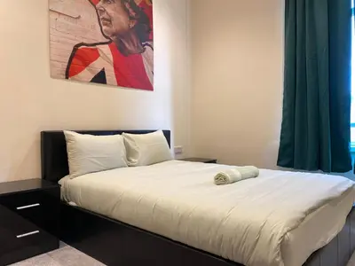 a bedroom with a bed with a painting on the wall at Springfield Guesthouse in Blackburn