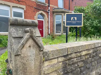 a sign on a retaining wall next to a building at Springfield Guesthouse in Blackburn