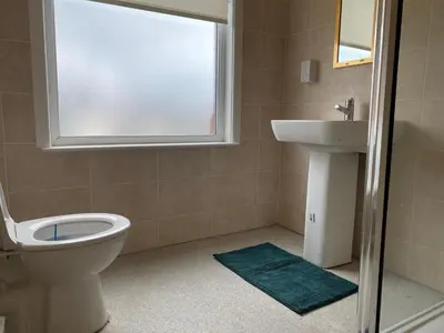 a bathroom with a toilet and a sink and a window at Springfield Guesthouse in Blackburn