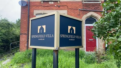 a sign in front of a building with a red door at Springfield Guesthouse in Blackburn