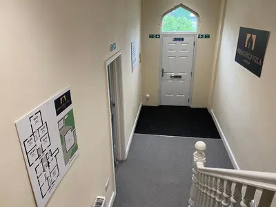 a hallway with a staircase and a white door at Springfield Guesthouse in Blackburn