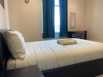 a bed with a pillow on it with a window at Springfield Guesthouse in Blackburn