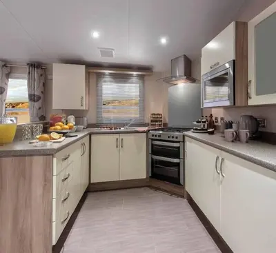 a kitchen with white cabinets and a stove top oven at Lagooncombe modern and cosy holiday home in Haverigg