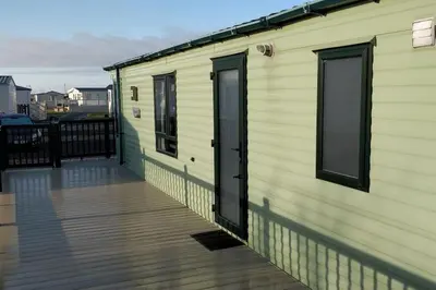 a house with a wooden deck with a building at Lagooncombe modern and cosy holiday home in Haverigg