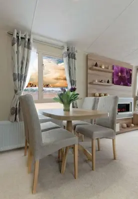 a dining room with a table and chairs and a window at Lagooncombe modern and cosy holiday home in Haverigg