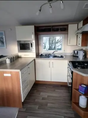 a kitchen with white cabinets and a sink and a window at Parkview, Port Haverigg in Haverigg