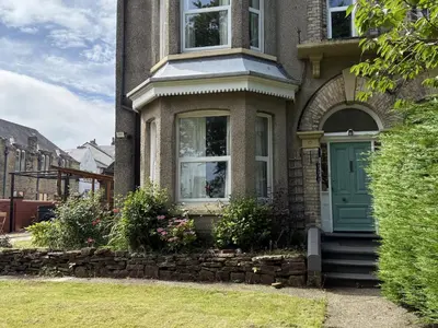 a house with a green door and a stone wall at The Furness Haven in Barrow in Furness