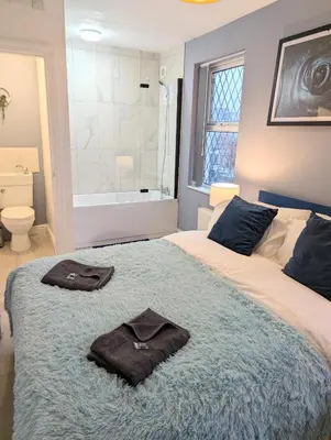 a bedroom with a bed with two towels on it at Blok 3 -Jacuzzi Suites, Apartment & Ensuite Rooms in Blackpool