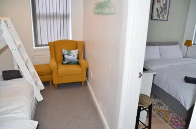 a room with two beds and a yellow chair and a window at Blok 3 -Jacuzzi Suites, Apartment & Ensuite Rooms in Blackpool