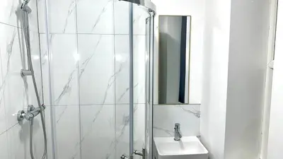 a bathroom with a shower and a sink and a mirror at Blok 3 -Jacuzzi Suites, Apartment & Ensuite Rooms in Blackpool