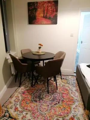 a dining room with a table and chairs on a rug at Blok 3 -Jacuzzi Suites, Apartment & Ensuite Rooms in Blackpool