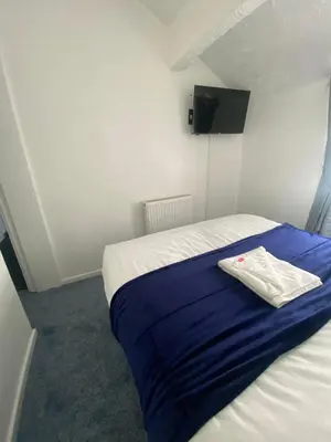 a small bedroom with a bed with a blue blanket at The New ATLAS HOTEL in Blackpool