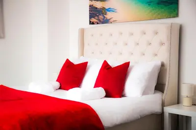 a red and white bed with red pillows on it at Lucky Home 24 - Ideal for Trade & Family - 2 Bedrooms - 3 Beds - Max 4 Guests - Close to BAE, Docks, Lake District, Beaches in Barrow in Furness