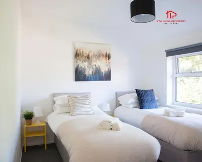 two twin beds in a room with a window at Spacious 7-Bed Home for Contractors & Families in St Helens in Saint Helens