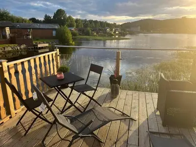two chairs and a table on a deck next to a lake at Gressingham 9 - South Lakes Leisure Village - lodge on the lake in Carnforth