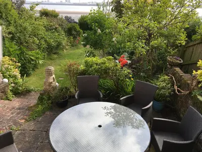 a white table and chairs in a garden at Millbrook by the sea in Wallasey