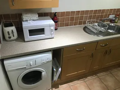 a kitchen with a washing machine and a microwave at Millbrook by the sea in Wallasey