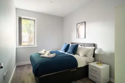 a bedroom with a bed with blue sheets and a window at Modern 1 Bed Apartment in Waterloo Liverpool in Liverpool