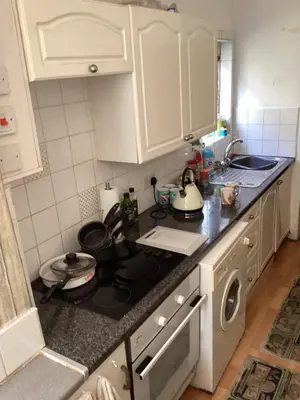 a kitchen with white cabinets and a stove top oven at The lavender house 513 halliwell rd bolton bl18db in Bolton