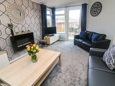 a living room with a vase of flowers on a coffee table at Park View Lodge, Arnside 7 in Carnforth